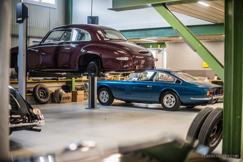 Ein oldtimer in einer alten garage mit einem mechaniker, der daran